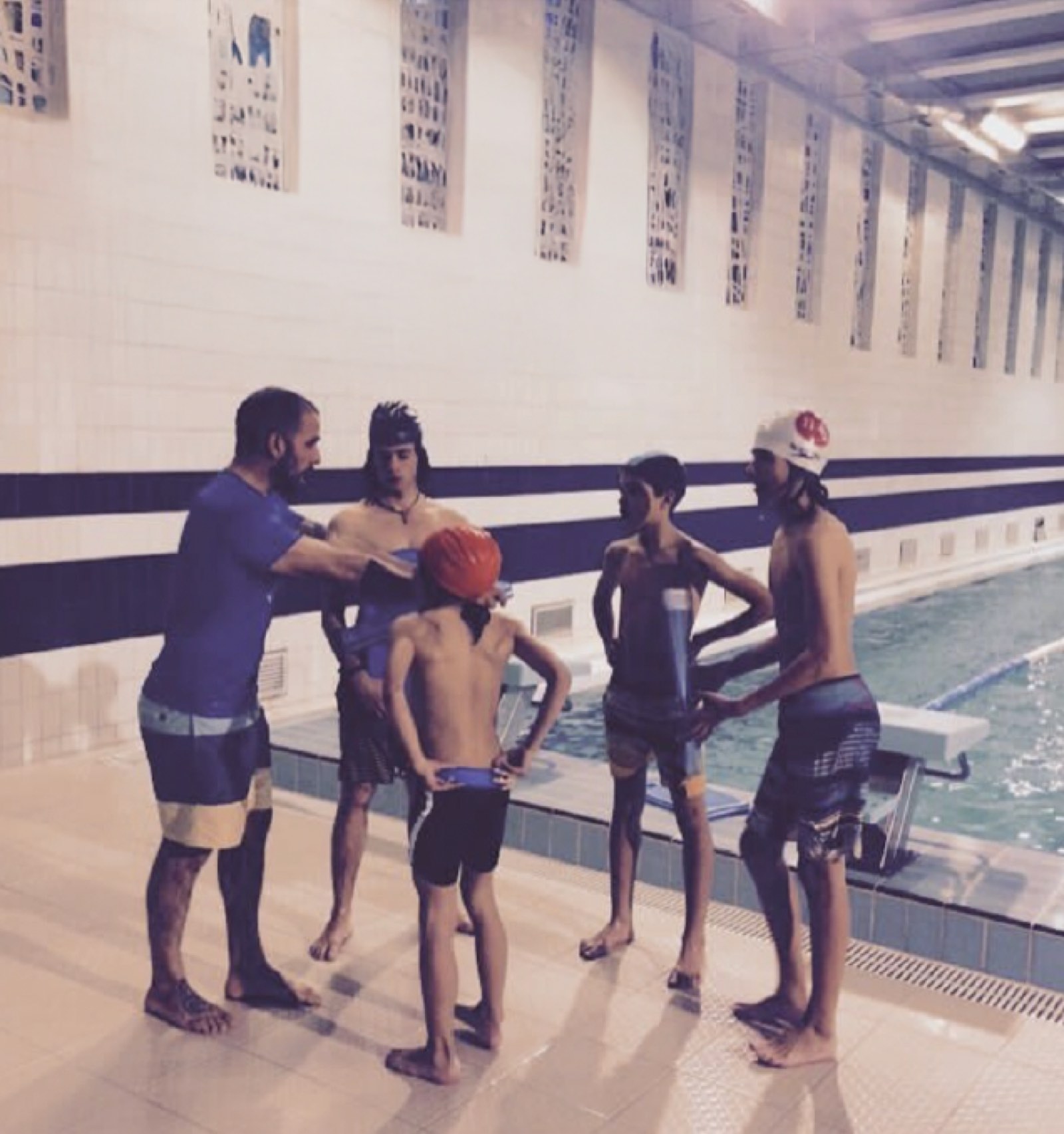 A coach guiding young athletes through pool-based ocean safety and conditioning training